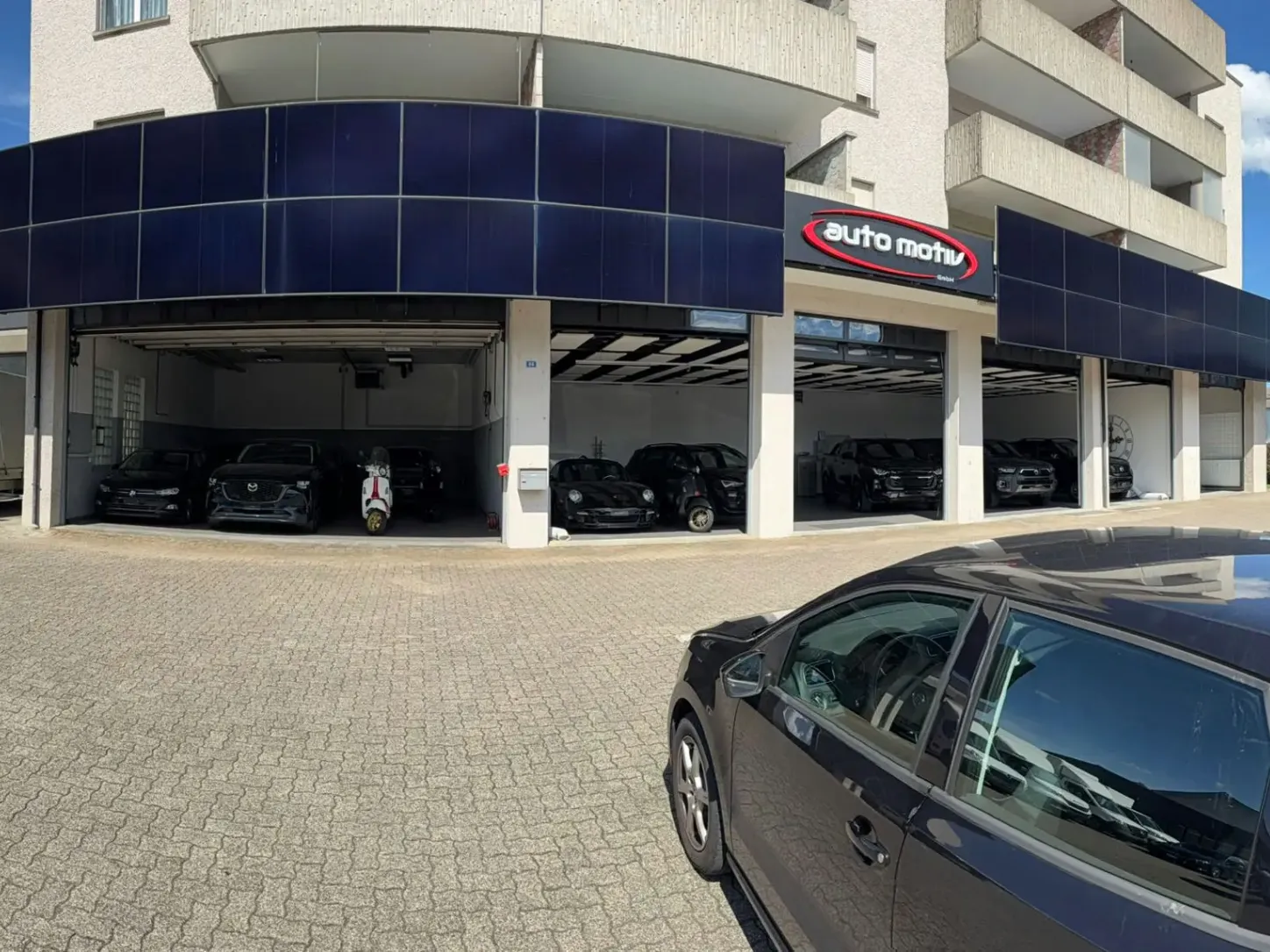 Autohaus mit dunklen Fahrzeugen auf dem Vorplatz